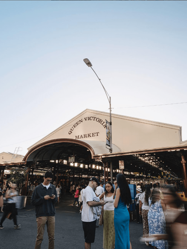 People standing in front of a shed labelled Queen Victoria Markets
