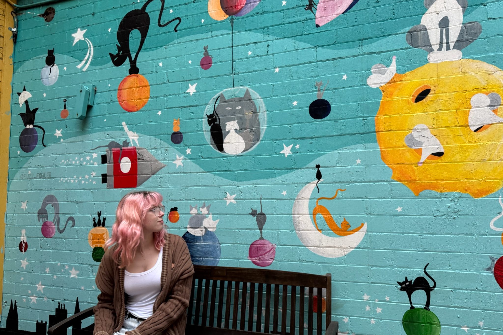 person sitting in front of cat mural